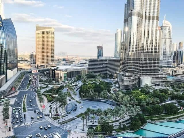 381 Woody Wood Web Web Design Development | Dubai Website Agency Aerial view of a modern city center with tall skyscrapers curved roads and a circular green plaza surrounded by palm trees and walkways