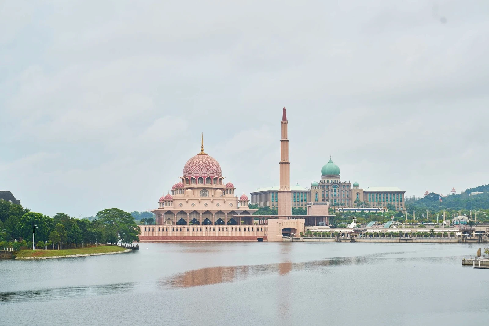 383 Woody Wood Web Web Design Development | Dubai Website Agency Pink domed mosque by a calm lake with a tall minaret and surrounding greenery on the shore