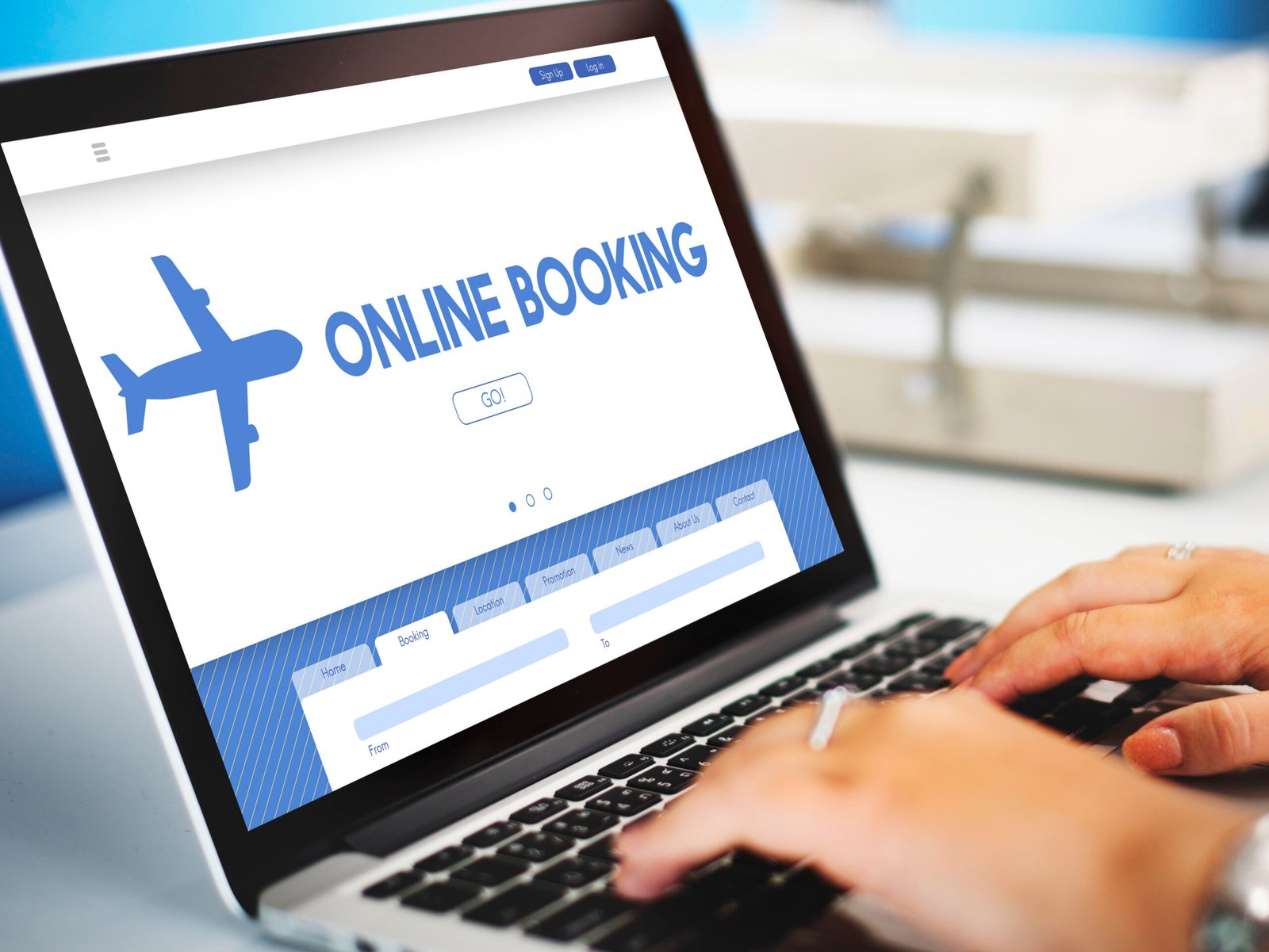 Laptop screen displaying an online booking page with a blue airplane graphic and a prominent ONLINE BOOKING header and a GO button visible